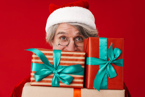 Obraz radosnego siwowłosy stary Święty Mikołaj człowiek trzyma pudełko prezentów - Zdjęcie, obraz