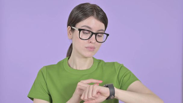 Молода жінка використовує Smart Watch на фіолетовому тлі
 - Фото, зображення