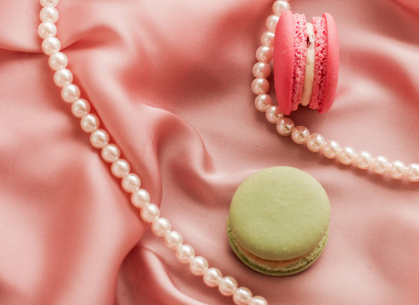 Sweet macaroons and pearls jewellery on silk background, parisia - 写真・画像