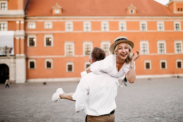Young man holding pretty woman on his hands on Stare Miasto in Warsaw Old Town  - Foto, imagen