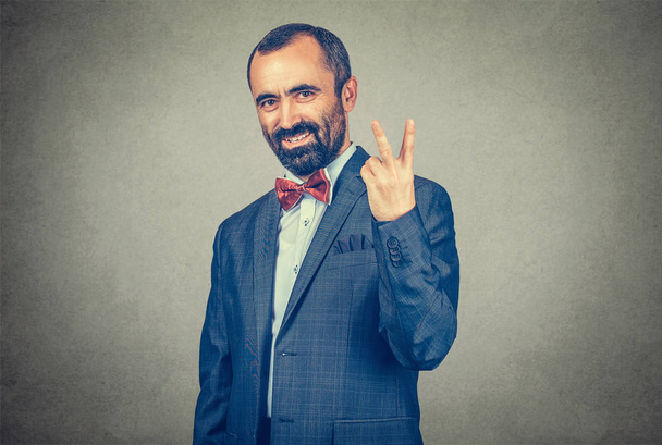 homem sorrindo com símbolo de sinal de mão vitória parede cinza isolado
 - Foto, Imagem