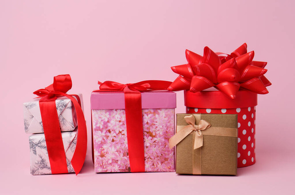 Stapel verpackter Geschenke mit geknüpften Schleifen auf rosa Hintergrund - Foto, Bild