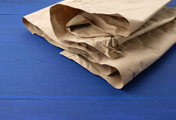 braunes zerknülltes Kraftpapier auf blauem Holzgrund - Foto, Bild