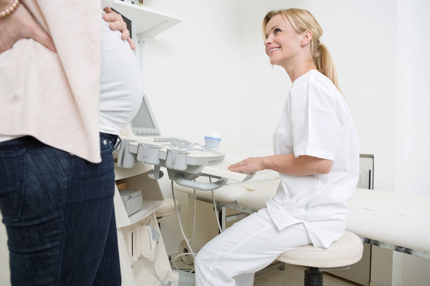 Médecin utilisant la machine à ultrasons tout en regardant la femme enceinte
 - Photo, image