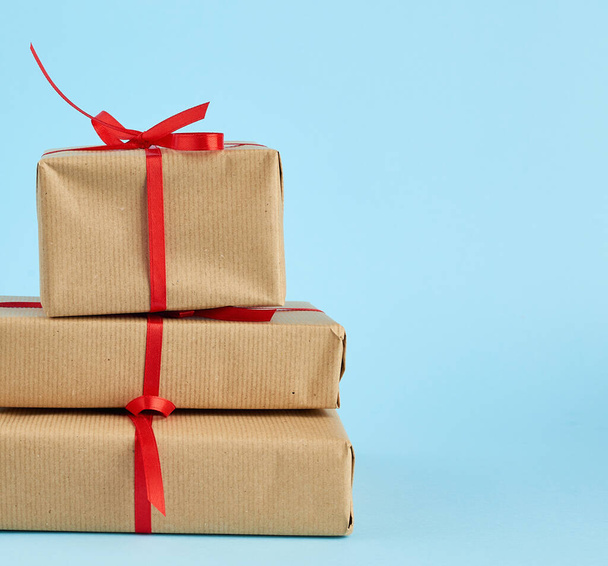stack of boxes wrapped in brown paper and tied with a red bow - 写真・画像