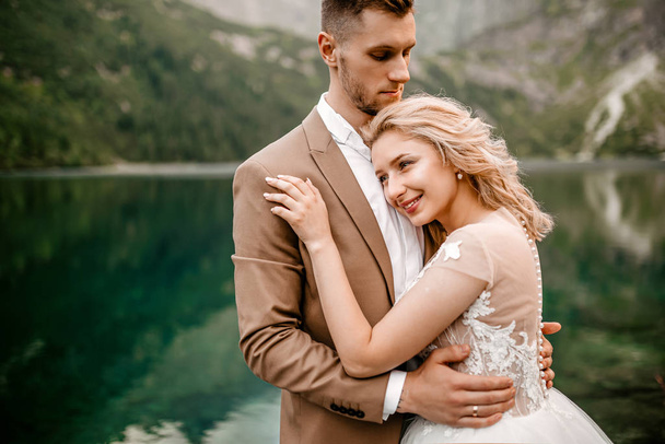 Retrato de noiva jovem incrível e noivo no lago Morskie Oko nas Montanhas Tatra, no sul da Polônia - Foto, Imagem