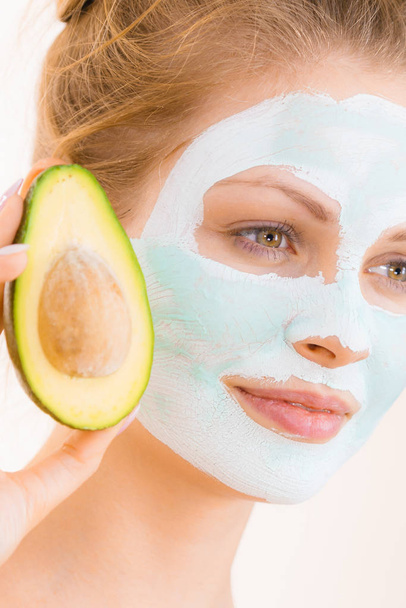 Girl facial mud mask holds avocado fruit - Zdjęcie, obraz
