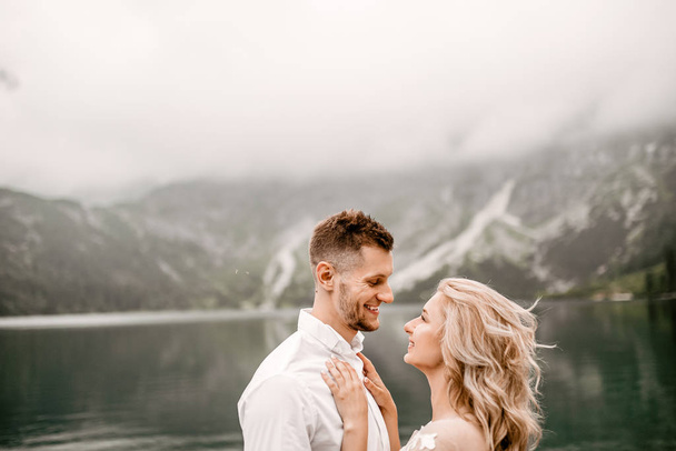 Beautiful young bride and groom on lake Morskie Oko in the Tatra Mountains, in southern Poland - Valokuva, kuva