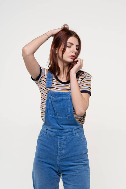 young beautiful girl is standing in blue overalls - Fotoğraf, Görsel