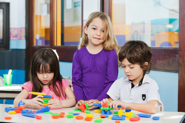 Девушка с друзьями играет в блоки в детском саду
 - Фото, изображение