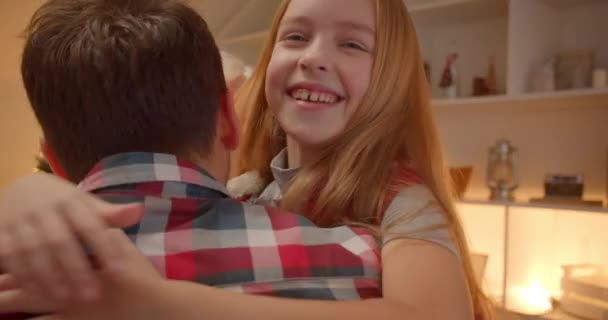 Little blonde girl hugs dad at Christmas family gift dinner evening - Materiał filmowy, wideo
