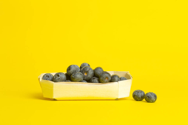 Bagas de mirtilo em um fundo amarelo. Uma dispersão de berrie
 - Foto, Imagem