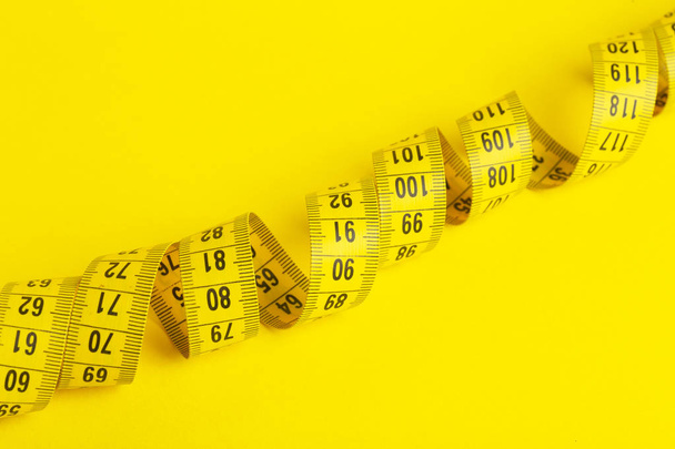 Measuring tape on a yellow background. Measuring tape in the sha - Photo, Image