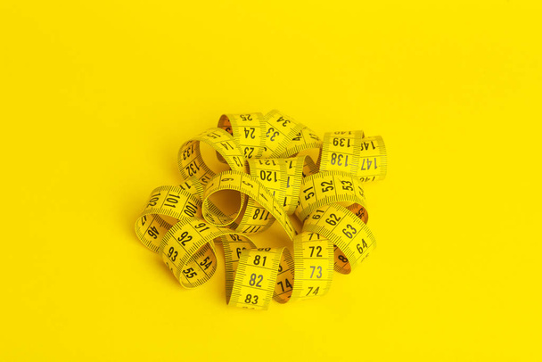 Measuring tape on a yellow background. Measuring tape in the sha - Photo, Image