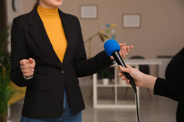 Профессиональный журналист опрашивает молодую женщину в комнате, крупным планом
 - Фото, изображение