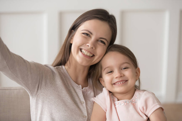 πορτρέτο της χαμογελαστής μητέρας με την κόρη της να βγάζει selfie - Φωτογραφία, εικόνα
