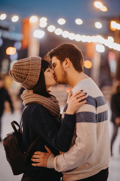 Young couple stands and kisses on the background city lights. - Фото, зображення