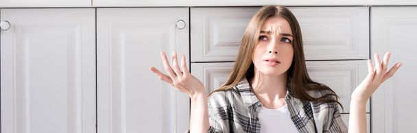 panoramic shot of confused woman doing shrug gesture in kitchen - Фото, зображення