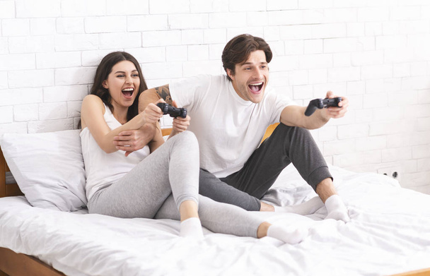 Emotionele echtgenoten genieten van videospelletjes in de slaapkamer - Foto, afbeelding
