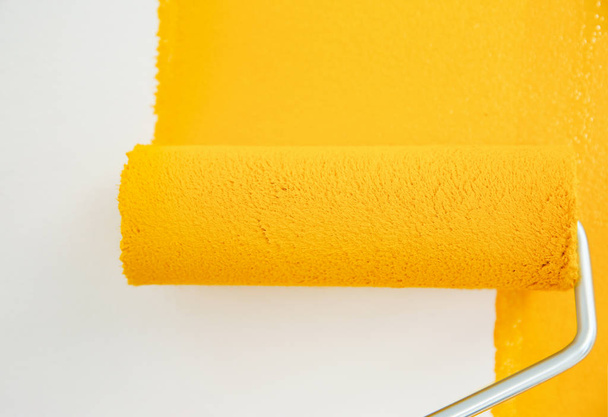 Painting white wall with yellow dye, closeup. Interior renovation - 写真・画像