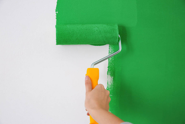 Yeşil boyalı beyaz duvarı boyayan kadın, yakın plan. İç yenileme - Fotoğraf, Görsel