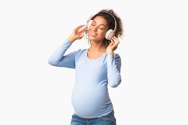 Pregnancy playlist. Afro expectant lady enjoying music - 写真・画像