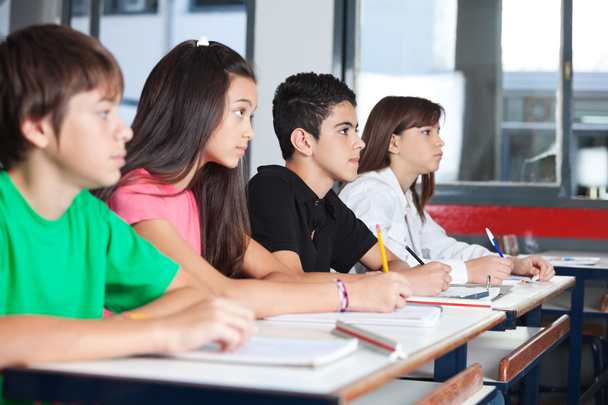 Teenage Students Looking Away While Studying At Desk - Fotó, kép