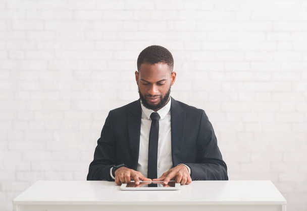 Young modern businessman using tablet, sitting at workplace - Φωτογραφία, εικόνα