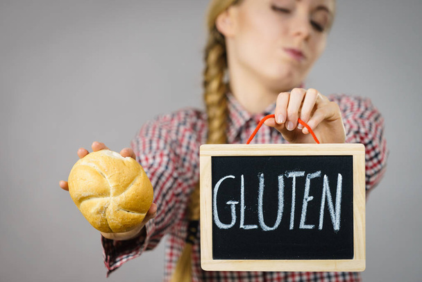 Woman holding board with gluten sign and bun bread - Foto, Imagen