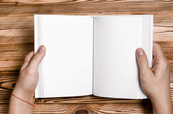 Männerhände mit aufgeschlagenem Buch mit leerem Einband auf hellem Hintergrund - Foto, Bild
