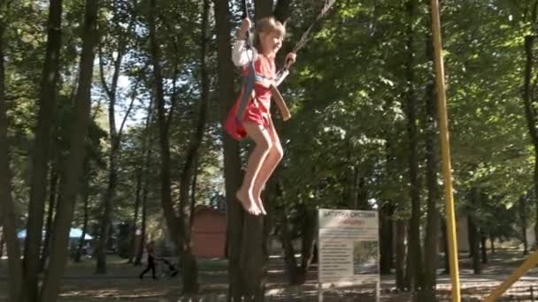 Gyermek lány ugrás rögzítve egy trambulinon a nyári parkban. - Felvétel, videó