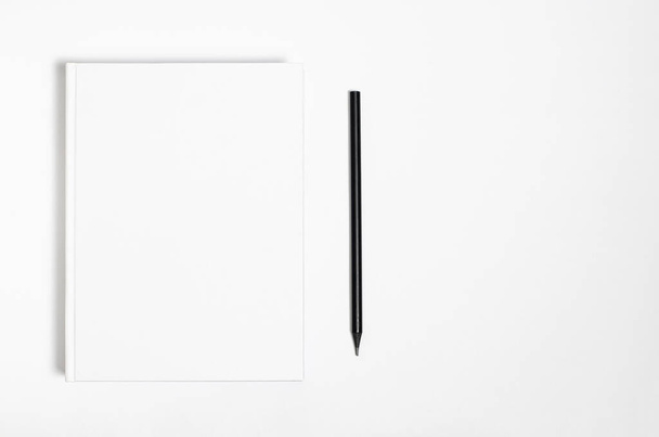 Mockup of closed blank square book and black pencil at white textured paper background - Foto, immagini