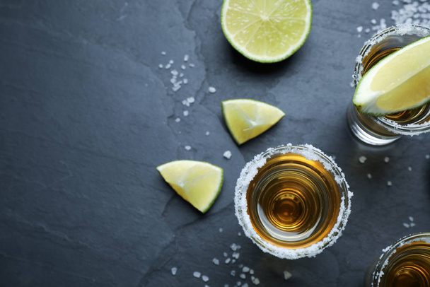 Mexican Tequila shots with salt and lime slices on grey table, flat lay. Space for text - Foto, imagen