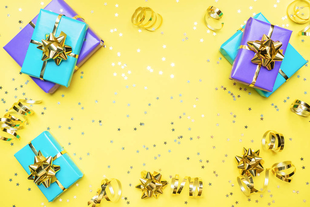 Gift boxes with gold ribbons and bows, confetti stars on a yellow background. Copy space Flat lay. Greeting card for birthday party, Christmas Wedding mother's Day. - Zdjęcie, obraz