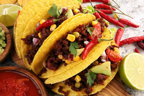 Meksikolaisia tacoja naudanlihalla, tomaateilla, avokadolla, chilillä ja sipulilla. H
 - Valokuva, kuva