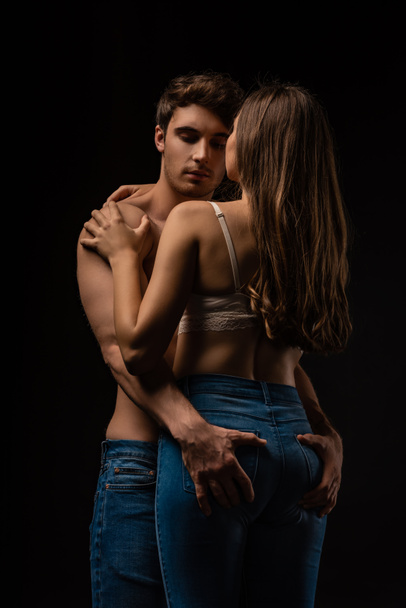 sexy young man touching girlfriend buttocks isolated on black - Foto, Imagen