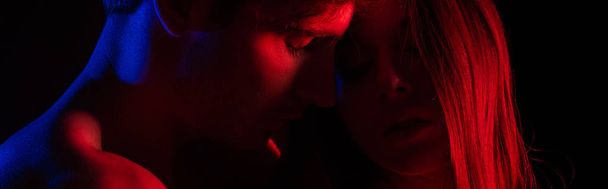 undressed sexy young couple kissing in red light isolated on black, panoramic shot - Фото, зображення