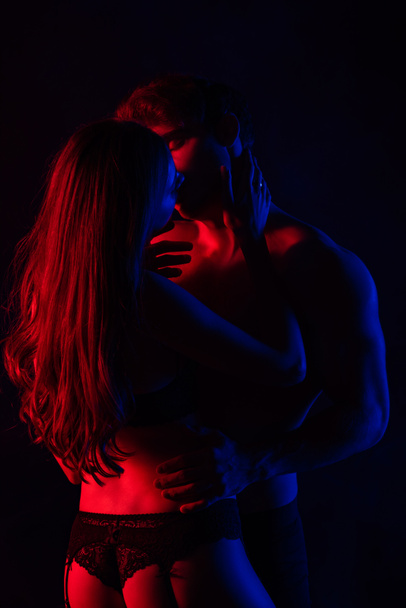 vášnivý svlečený sexy mladý pár líbání v červeném světle izolované na černé - Fotografie, Obrázek
