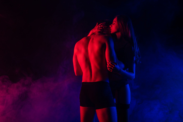 страстная раздета сексуальная молодая женщина целует парня в красном свете
 - Фото, изображение