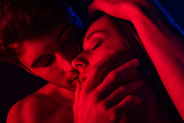 παθιασμένος γυμνός σέξι άντρας να φιλάει γυναίκα στο κόκκινο φως - Φωτογραφία, εικόνα