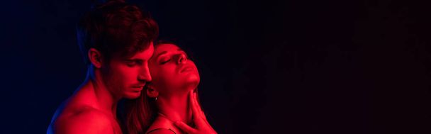 passionate undressed sexy young couple in red light isolated on black, panoramic shot - Photo, Image
