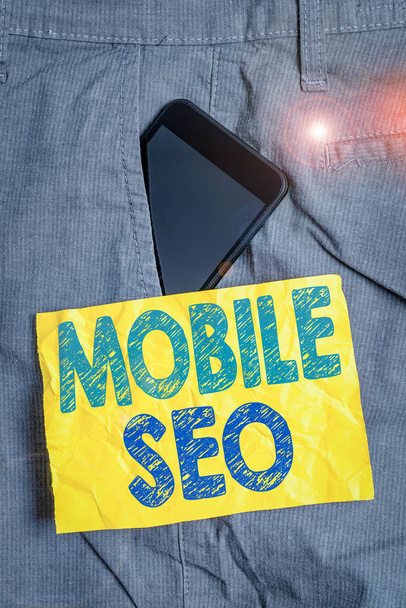 Writing note showing Mobile Seo. Business concept for process of optimizing a website to rank for mobile searches Smartphone device inside trousers front pocket note paper - Photo, Image