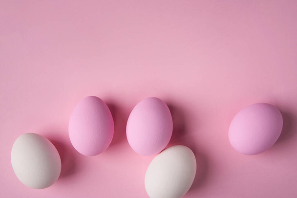 Easter eggs scattered on pink background with copy space above - Fotoğraf, Görsel