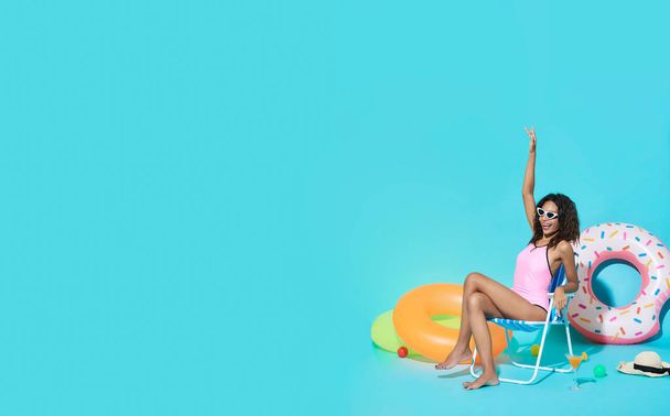 Heureuse jeune femme africaine vêtue de maillots de bain geste dire bonjour et profiter de leurs vacances d'été escapade en fond de bannière bleue avec espace de copie
. - Photo, image