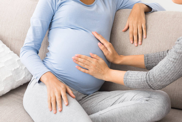 Nainen vierailee raskaana ystävä ja koskettaa vatsa
 - Valokuva, kuva