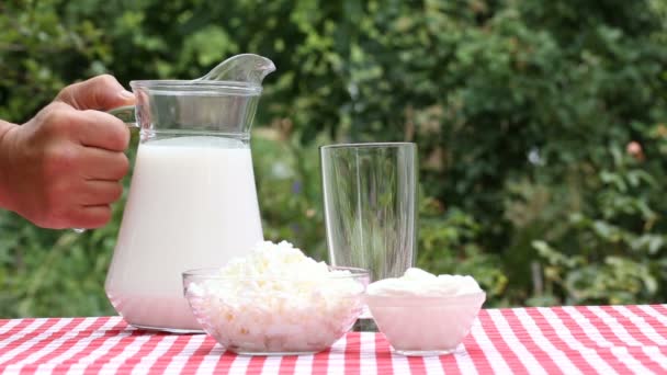 Kézzel öntött tej a kancsó az üvegbe - Felvétel, videó