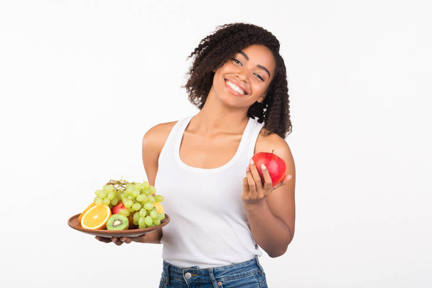Lächelnde schwarze Frau steht mit Früchten im Atelier - Foto, Bild