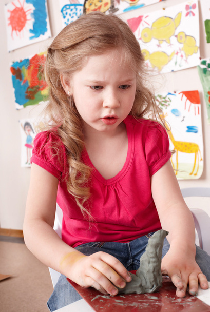 Дитяча дівчина формується з глини в ігровій кімнаті
. - Фото, зображення