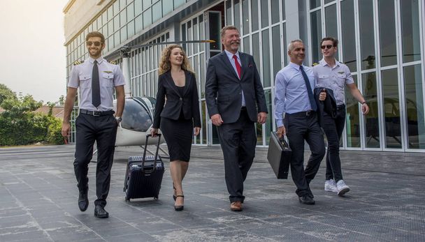 Successful intelligent smart elegant business people with team walking together near helicopter - Photo, Image