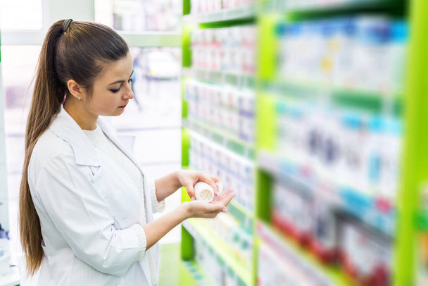 Chemist looking at tablets in her palm - Photo, Image